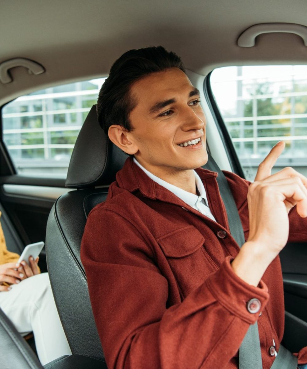 smiling-taxi-driver-and-passenger-with-smartphone-in-car-e1635074849312.jpg